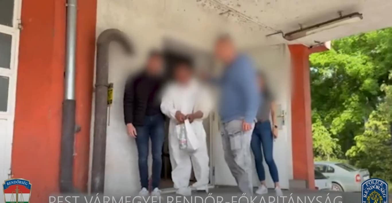 emberek, egyikük bilincsben egy épület előtt