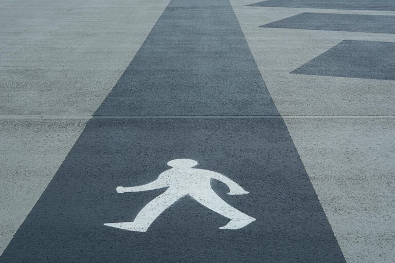 Close-up of a marked pedestrian crossing symbol on a concrete pathway.