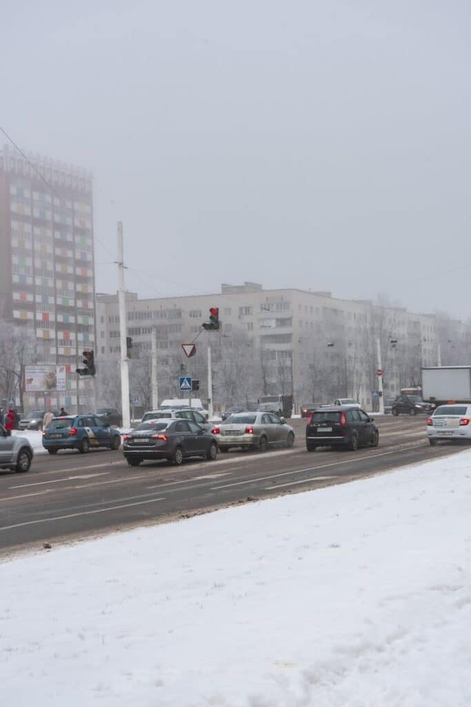 Snow-covered city street in Vitebsk, Belarus with winter traffic and urban buildings.