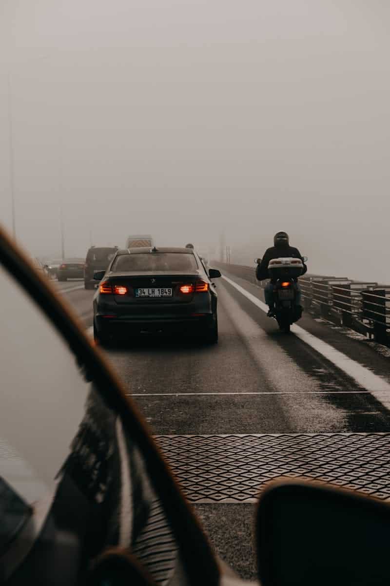 A misty highway scene with cars and a motorbike in traffic, emphasizing travel and transportation.