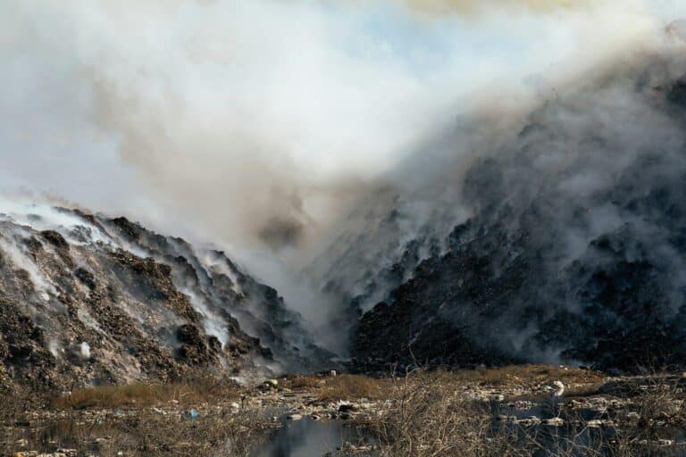 a mountain covered in smoke next to a body of water