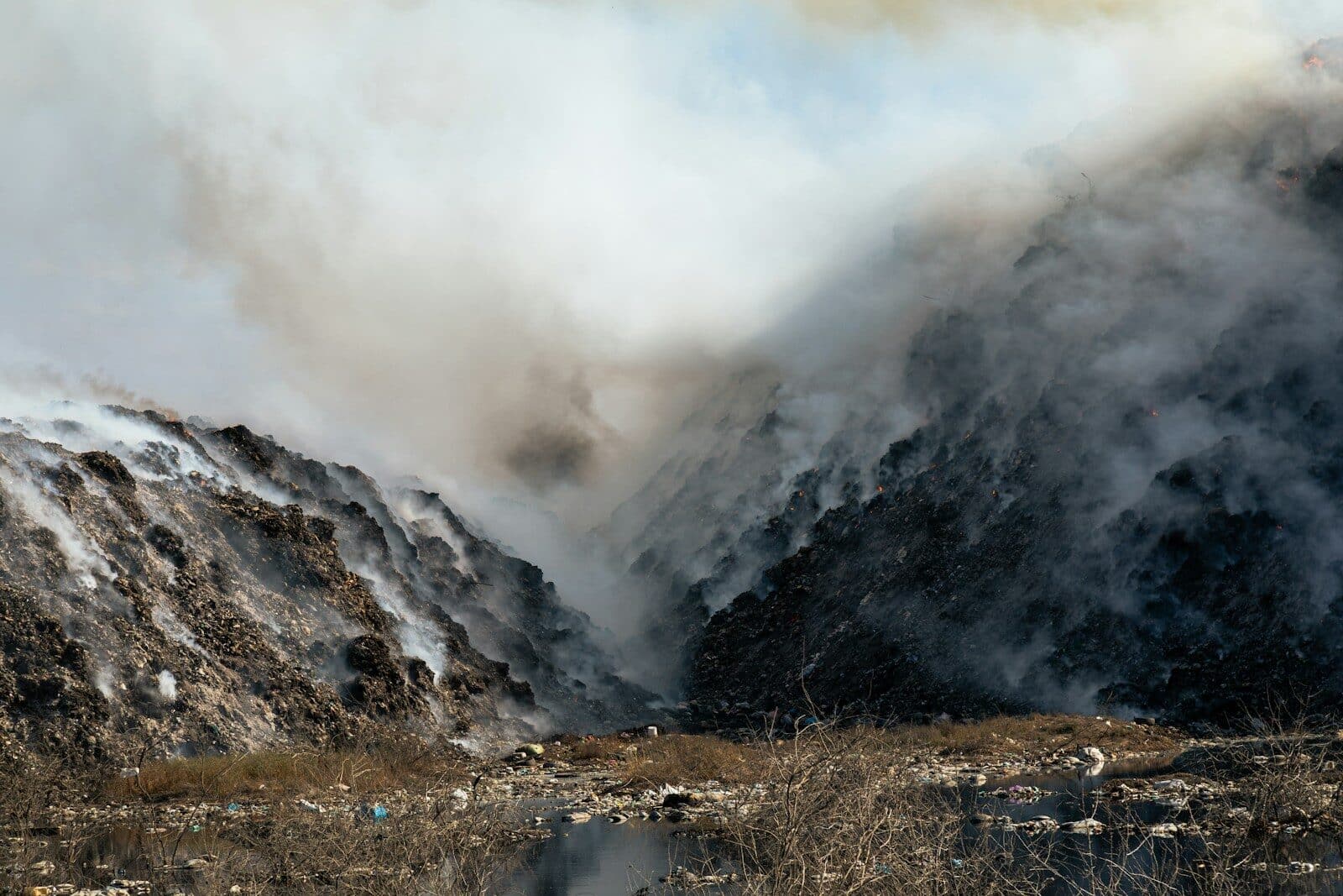 a mountain covered in smoke next to a body of water