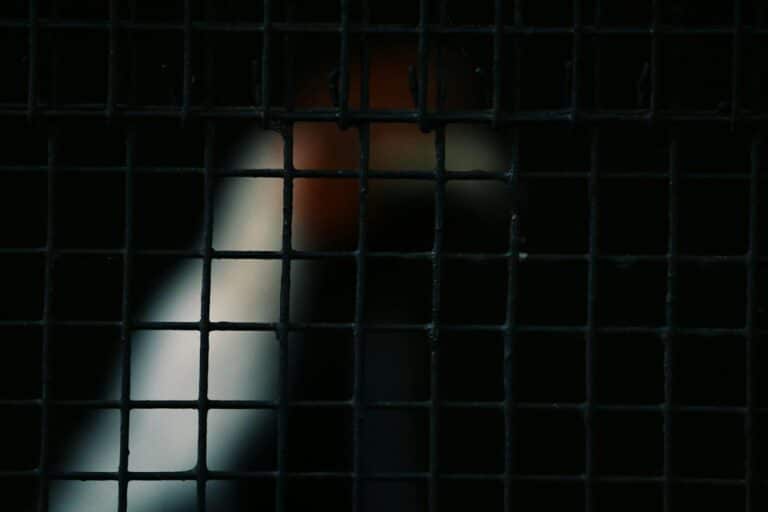 Close-up of a metal grid with abstract light patterns in the background, creating a mysterious atmosphere.