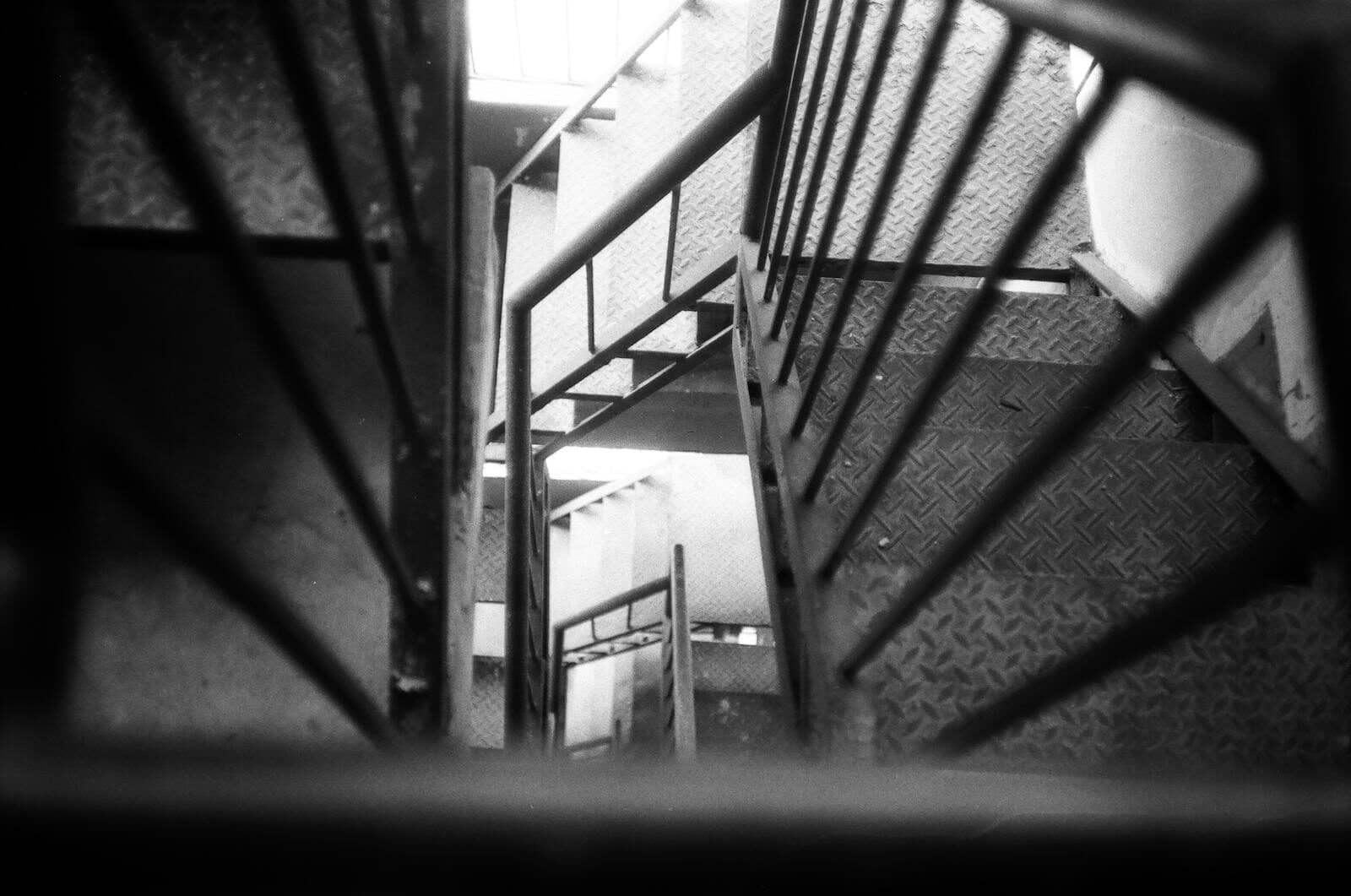 Artistic black and white shot of a staircase with metal handrails in an industrial setting.