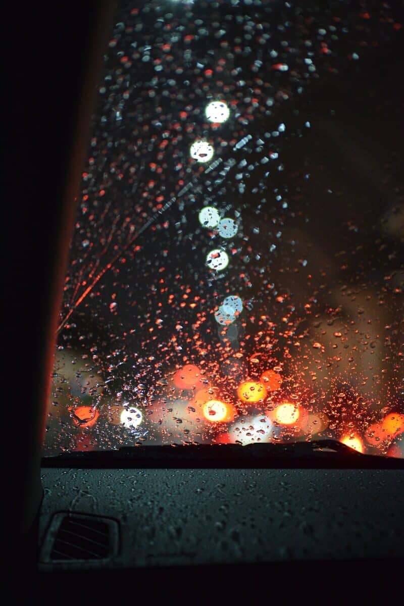 A view of a rain covered windshield from inside a car