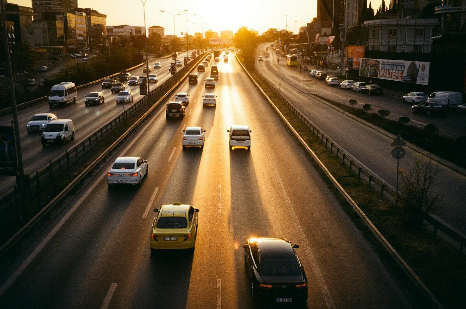 Multiple lane highway with cars moving in sunset light, symbolizing urban transportation.
