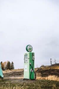 a green gas pump sitting on top of a grass covered field