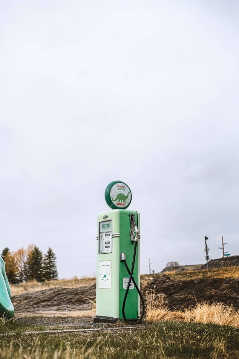 a green gas pump sitting on top of a grass covered field