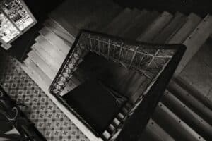 Artistic top view of a spiral staircase in black and white, featuring ornate railings.
