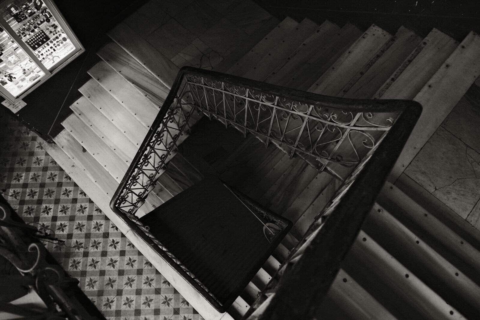 Artistic top view of a spiral staircase in black and white, featuring ornate railings.