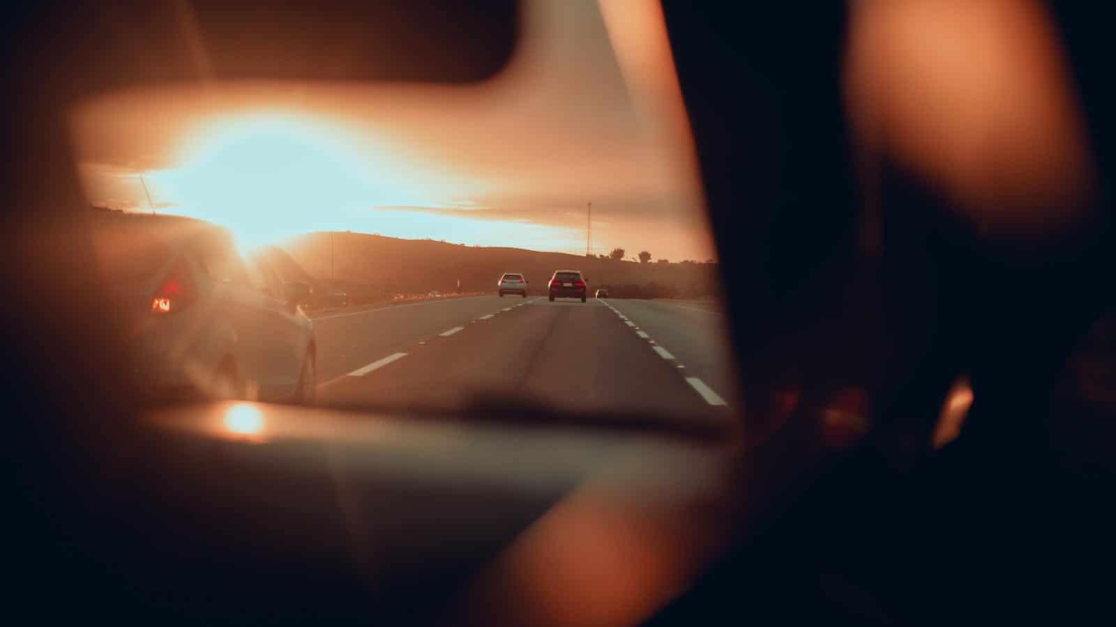 Sunset view of cars driving on a highway, captured from a vehicle's interior.
