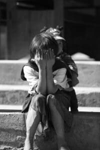 Black and white portrait of two children sitting outdoors in Myanmar.
