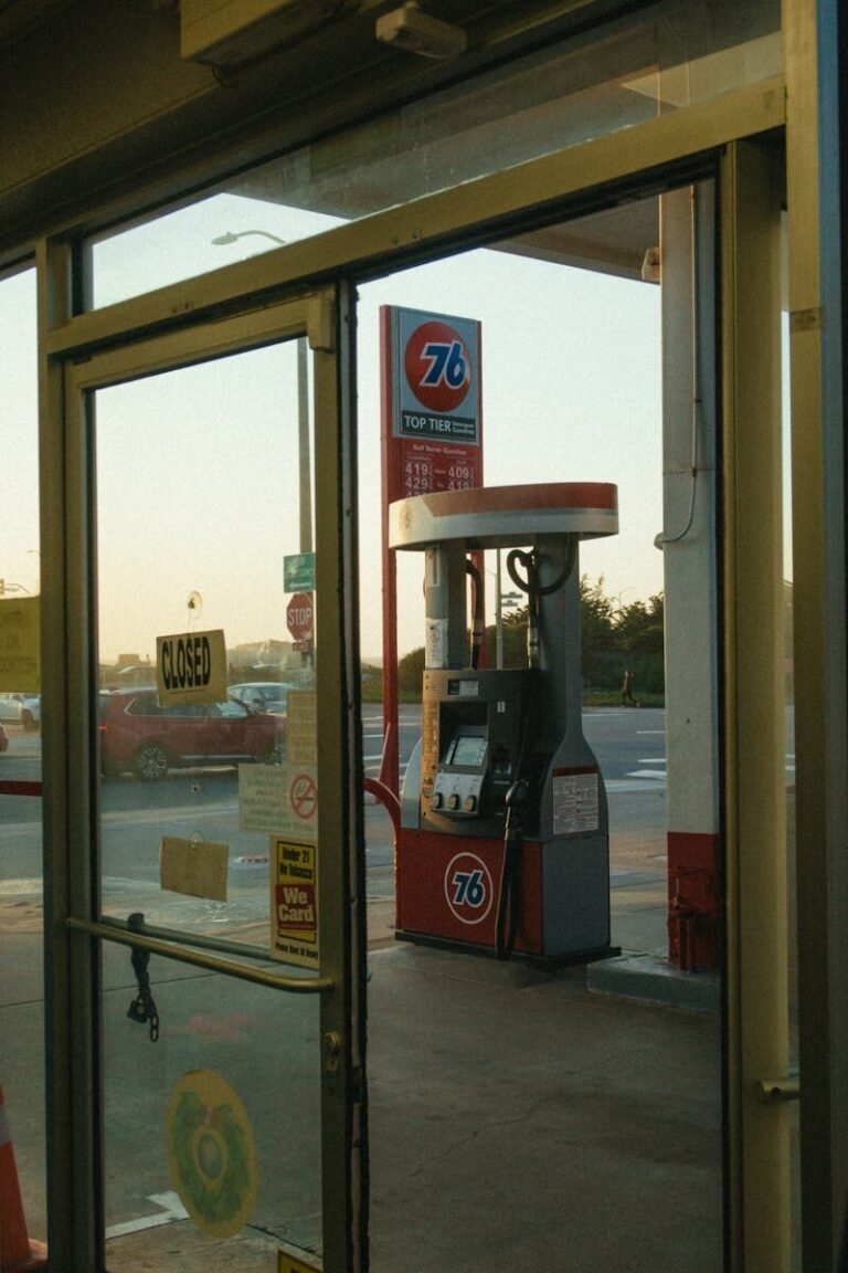 Image of a classic gas station pump viewed through a glass door at sunset.