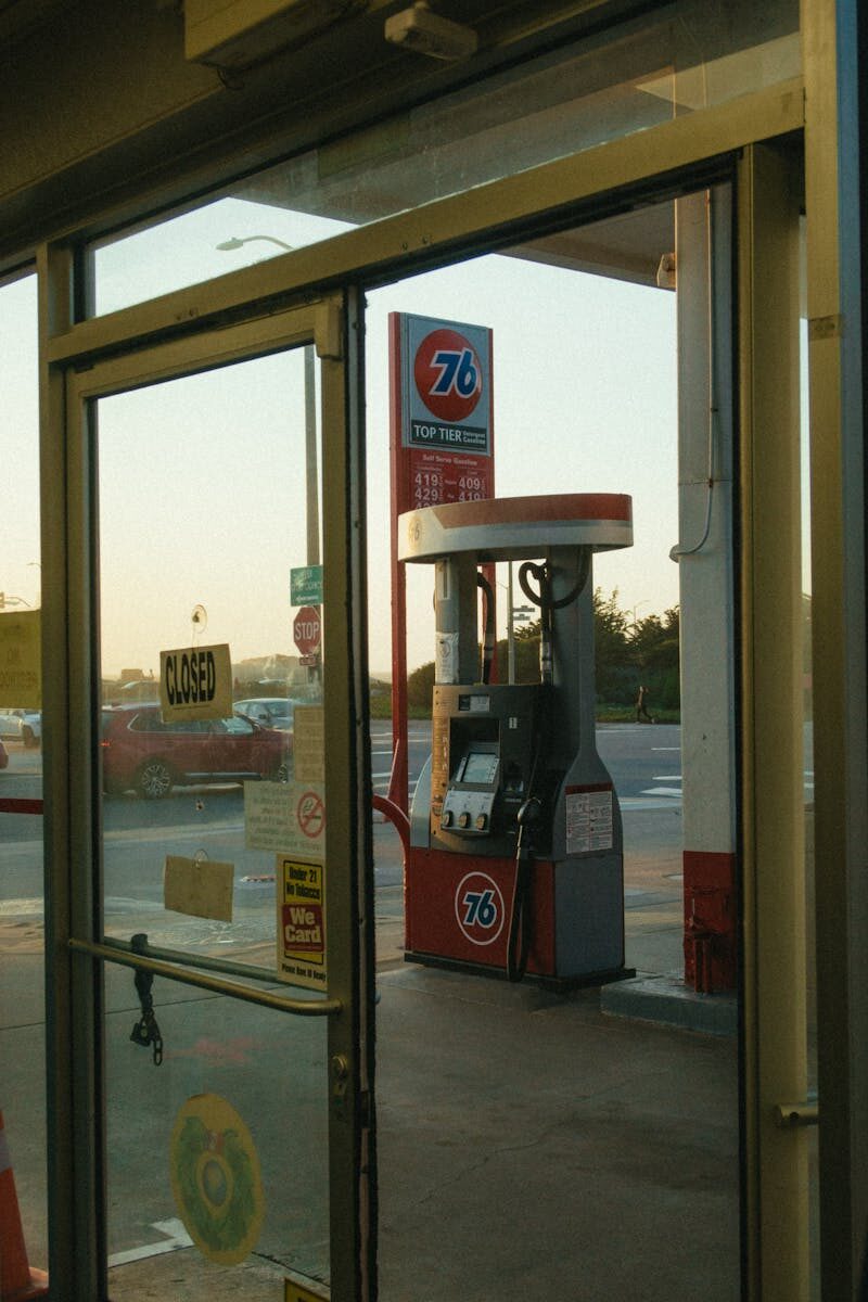 Image of a classic gas station pump viewed through a glass door at sunset.