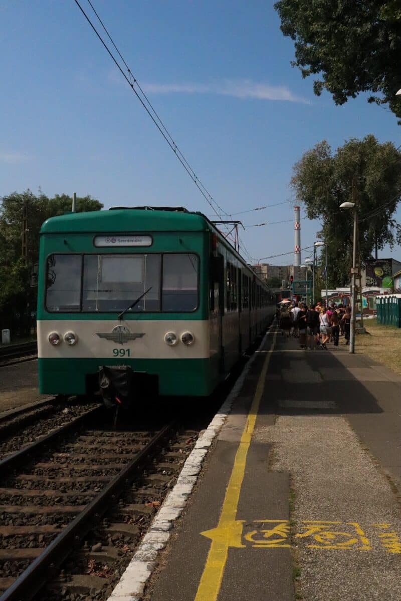 A green train is stopped at a station.