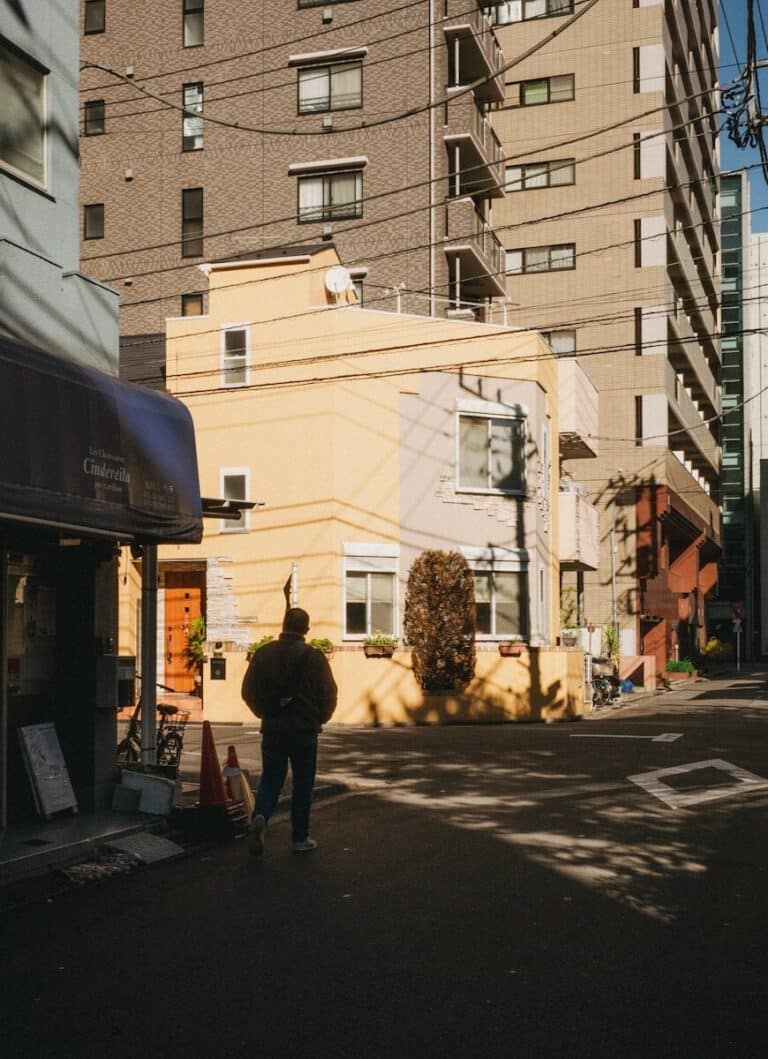 A person walks down a narrow street between buildings.