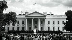 The white house stands with people gathered nearby.