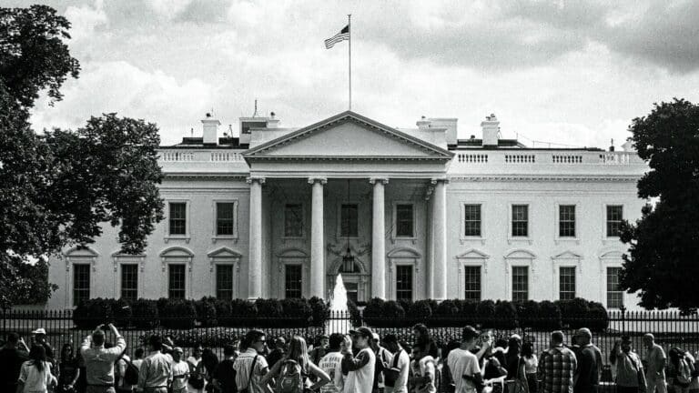 The white house stands with people gathered nearby.