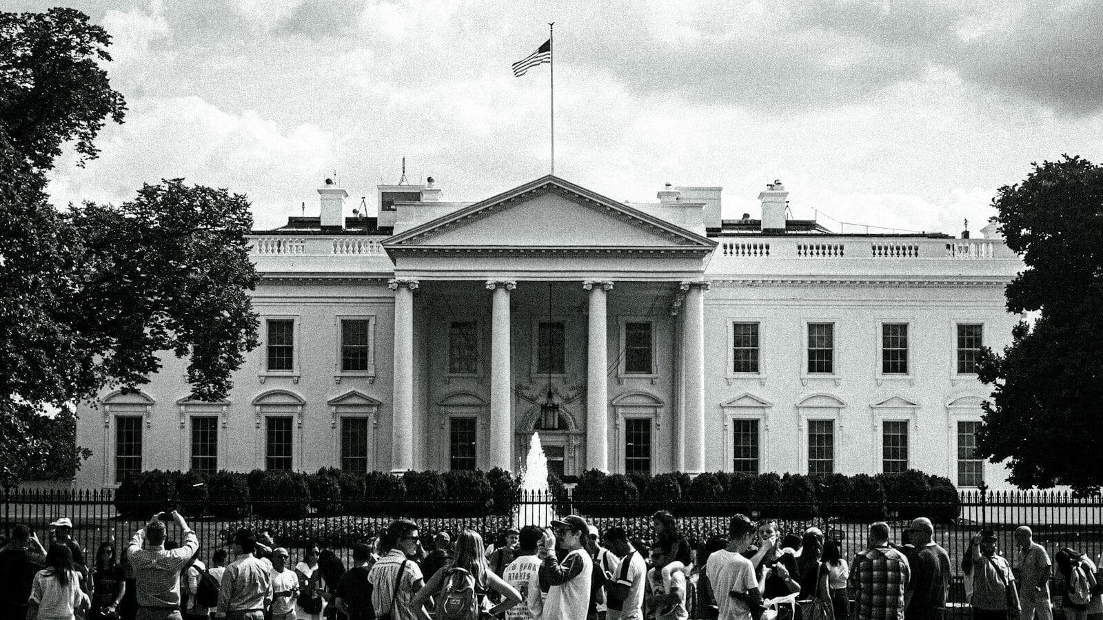 The white house stands with people gathered nearby.