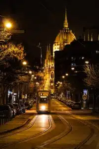 Night view of a tram with Budapest Parliament in the background, beautifully lit.