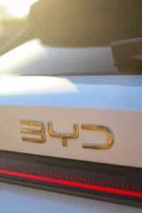 Gold byd emblem on white car with red light.