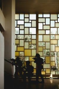 Silhouetted soldiers move cautiously near a patterned window.