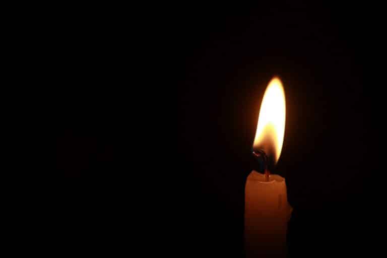 a lit candle in the dark with a black background