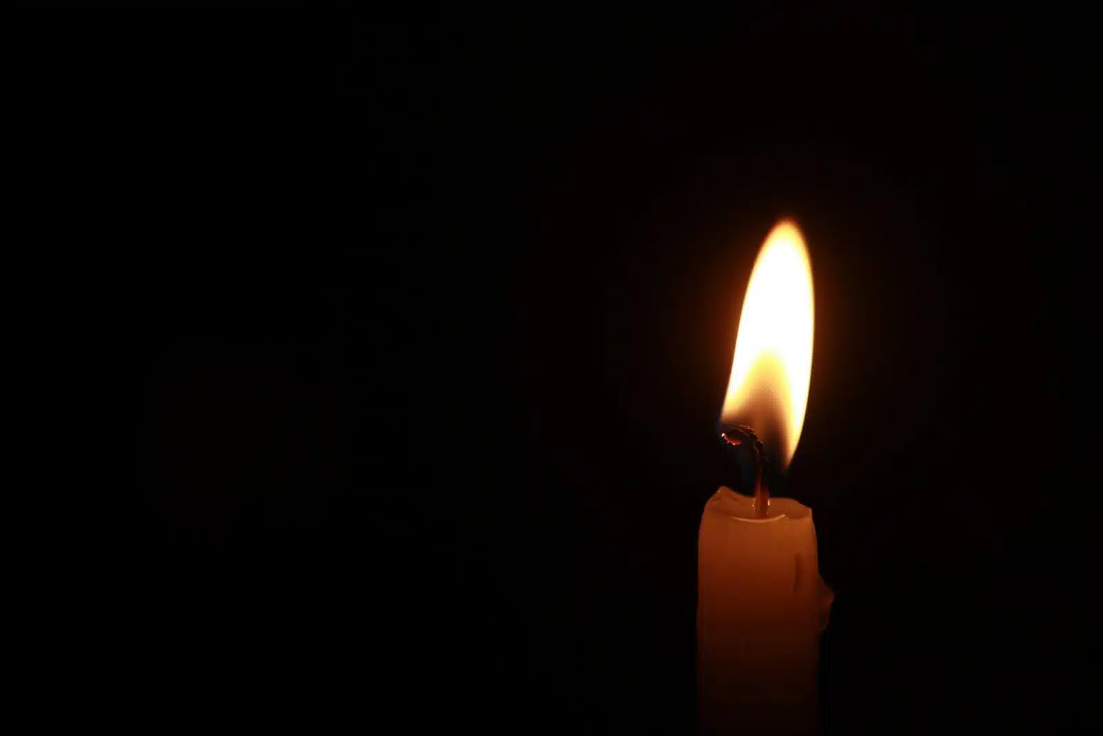 a lit candle in the dark with a black background