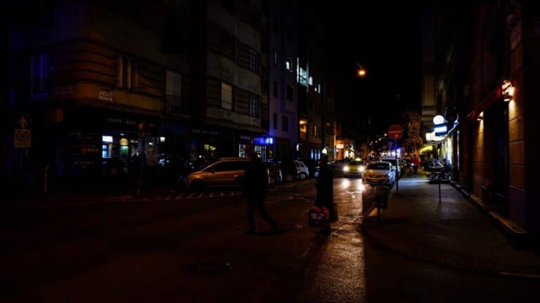 a couple of people walking down a street at night
