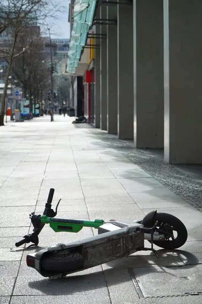 A lime scooter lies abandoned on a sidewalk.