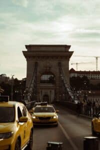 Yellow taxis on a bridge with a stone archway.