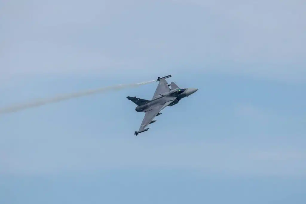 a fighter jet flying through a blue sky