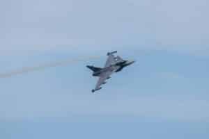 a fighter jet flying through a blue sky