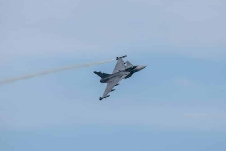 a fighter jet flying through a blue sky