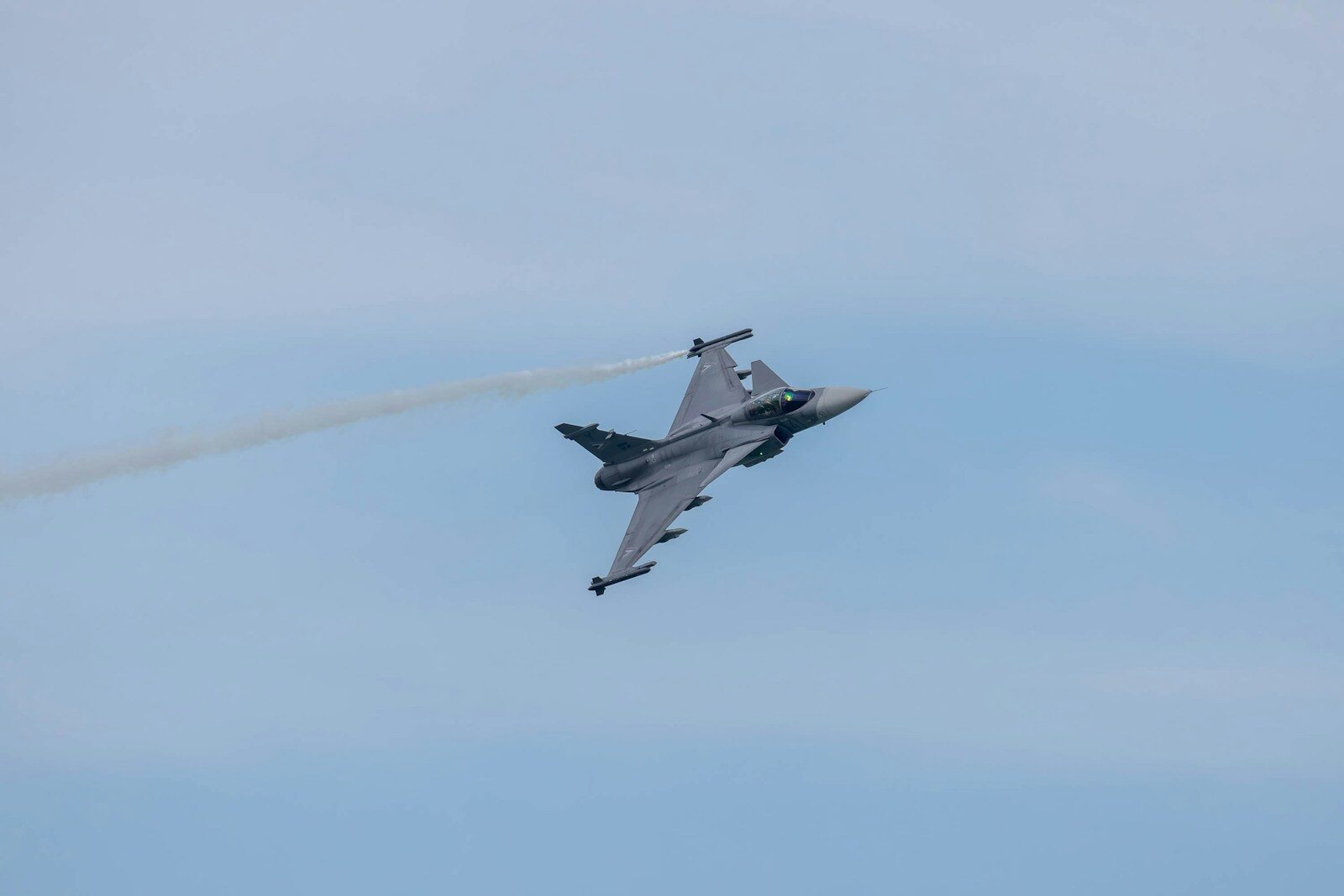 a fighter jet flying through a blue sky