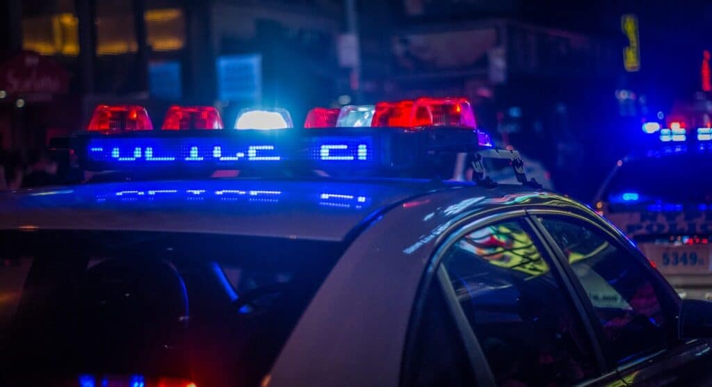 A police car with flashing red and blue emergency lights on a city street