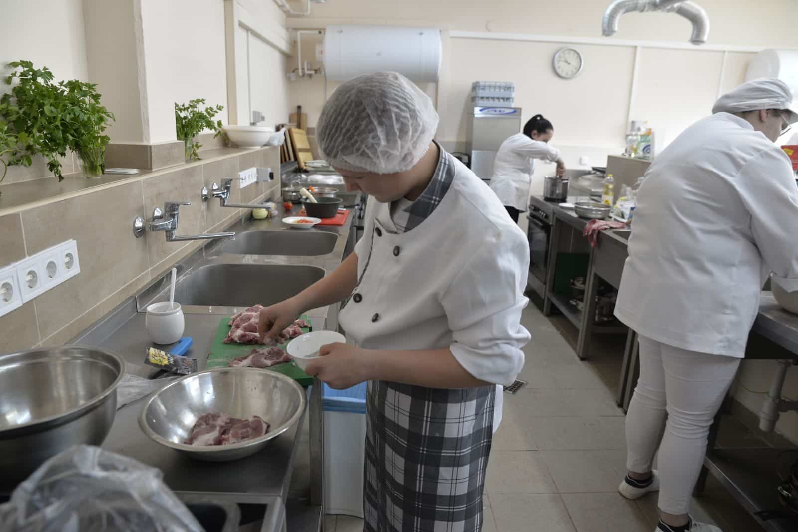 Culinary students practicing cooking skills in a professional kitchen setting, showcasing teamwork and education.