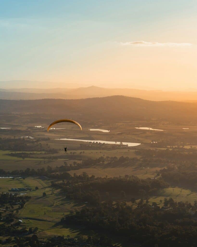 person paragliding above countryside during daytime