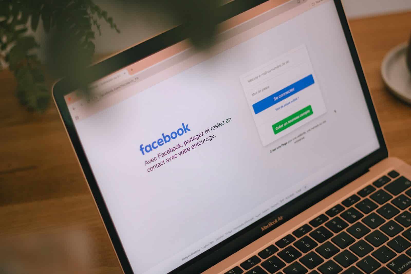 A laptop displays the facebook login page