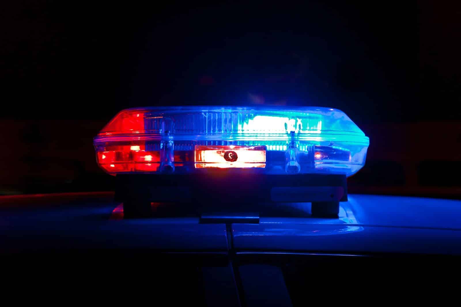 A police light bar flashing red and blue against a dark night background